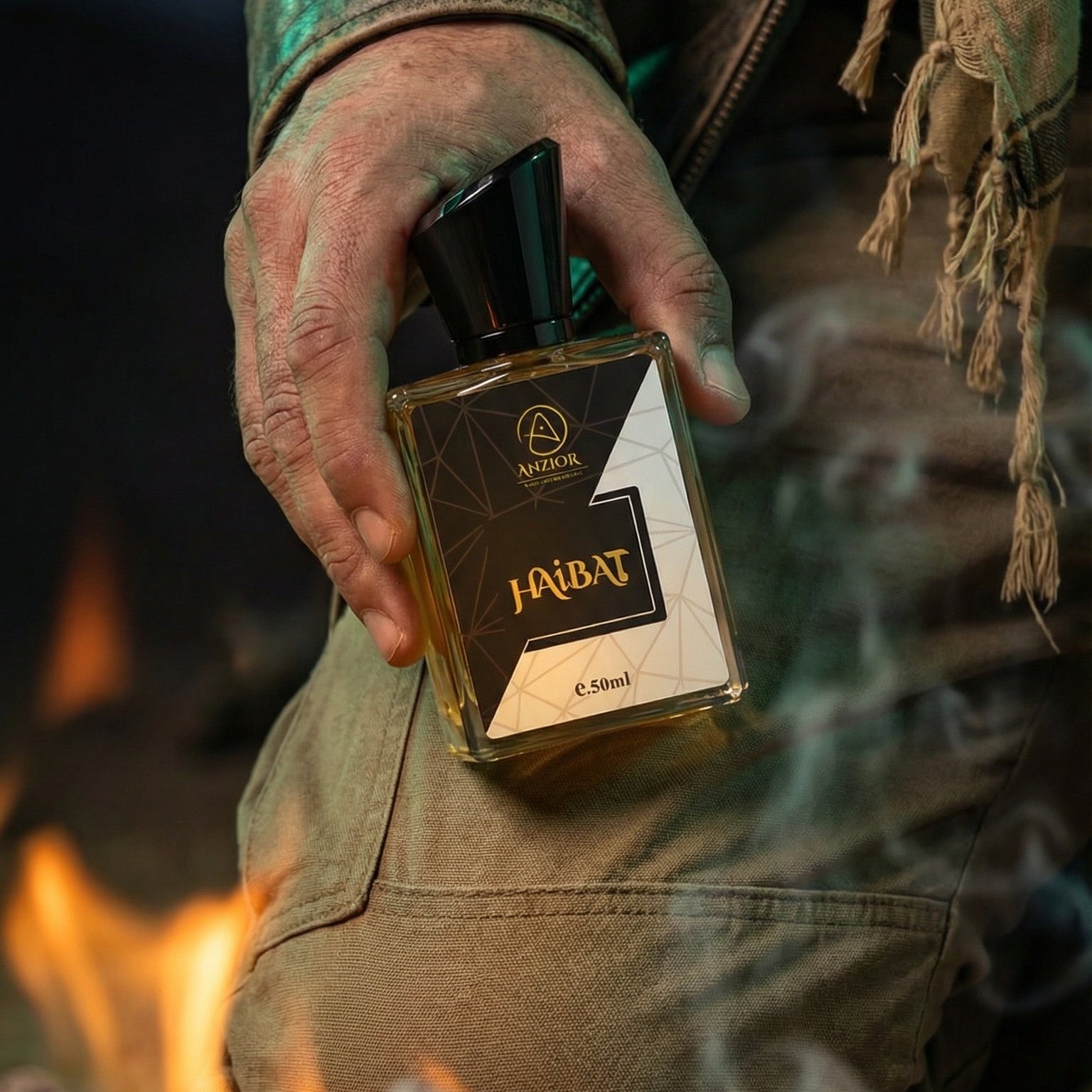 Hand holding a bottle of Haibat By  Anzior perfume in front of a fire